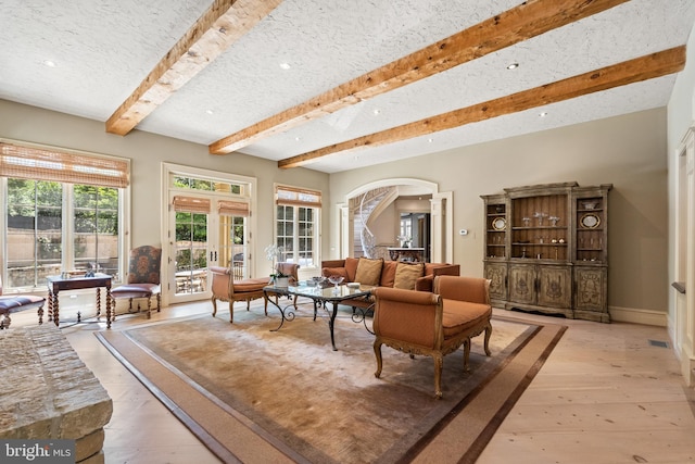 living room featuring a textured ceiling, beam ceiling, and light hardwood / wood-style floors