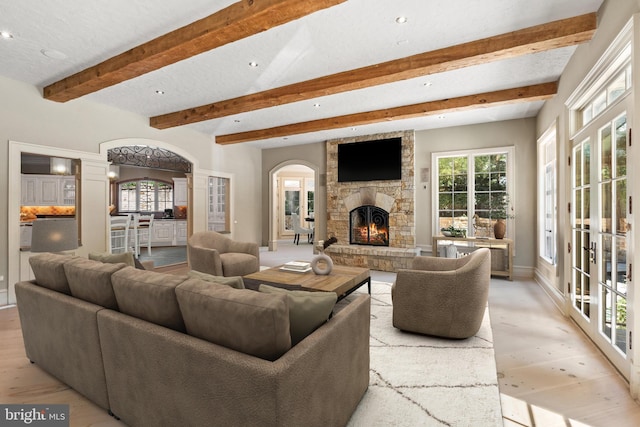 living room featuring a fireplace, plenty of natural light, light hardwood / wood-style floors, and ornate columns