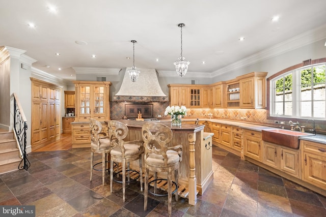 kitchen with pendant lighting, sink, a breakfast bar area, a center island, and custom range hood