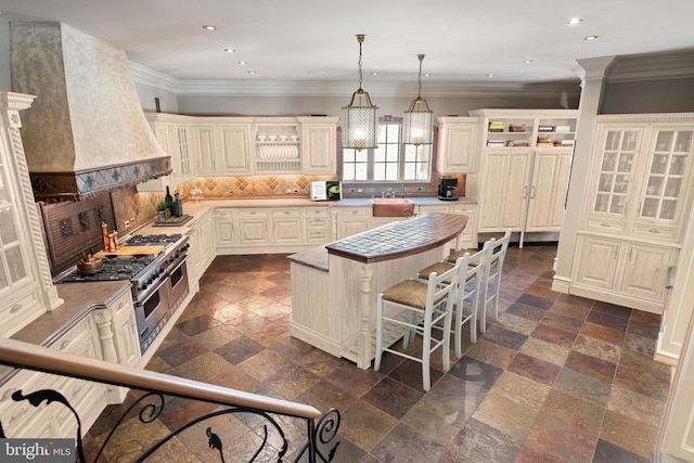 kitchen featuring premium range hood, a breakfast bar area, decorative backsplash, hanging light fixtures, and a center island