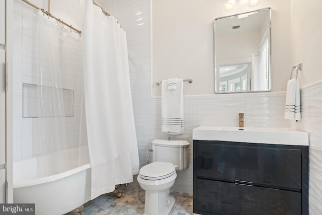 full bathroom with tile walls, vanity, toilet, and shower / bath combo with shower curtain