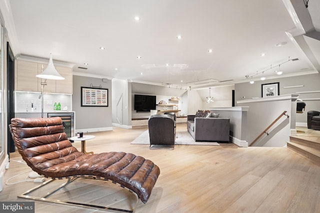 living room with wine cooler, track lighting, ornamental molding, and light wood-type flooring