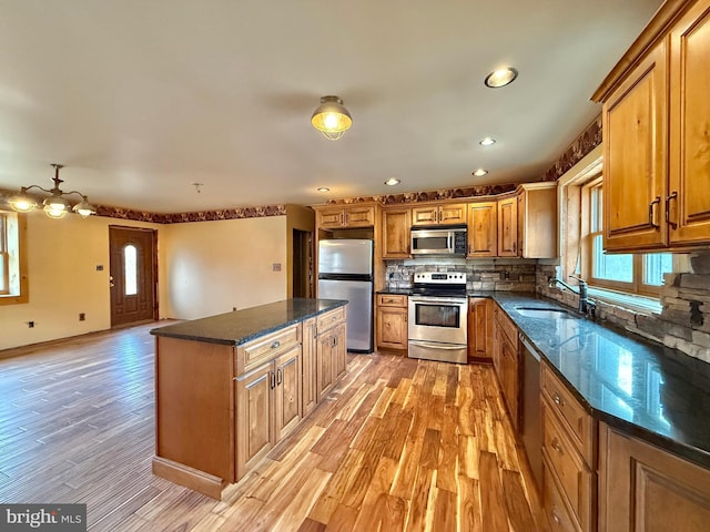 kitchen featuring a kitchen island, sink, stainless steel appliances, and light hardwood / wood-style flooring