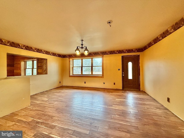 foyer with hardwood / wood-style flooring, plenty of natural light, and a chandelier