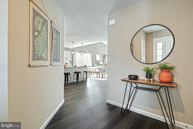 corridor with dark hardwood / wood-style flooring, lofted ceiling, and a notable chandelier