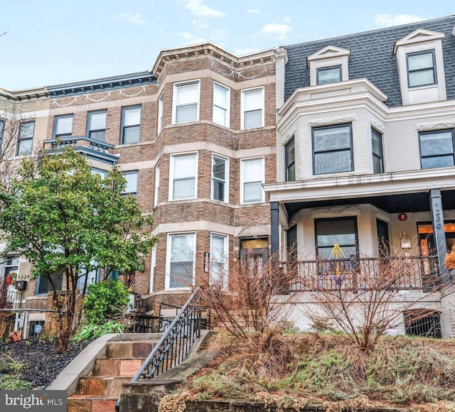 townhome / multi-family property featuring stairway, brick siding, and roof with shingles