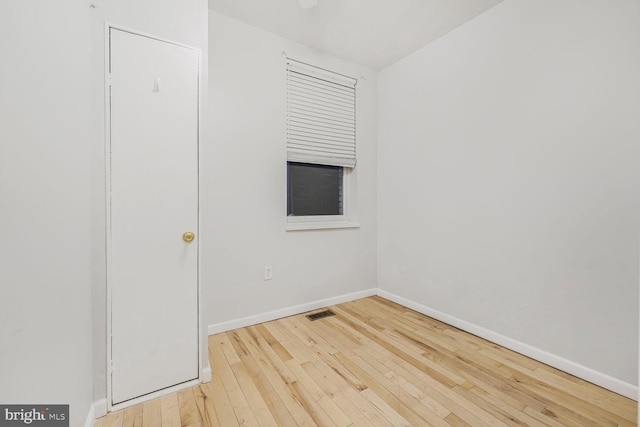 unfurnished room with hardwood / wood-style floors, visible vents, and baseboards