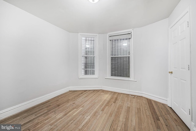 unfurnished room with hardwood / wood-style floors and baseboards