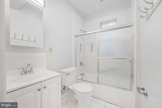 full bath with tile patterned flooring, enclosed tub / shower combo, vanity, and toilet