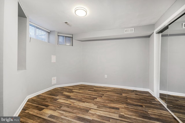 basement featuring baseboards, visible vents, and wood finished floors