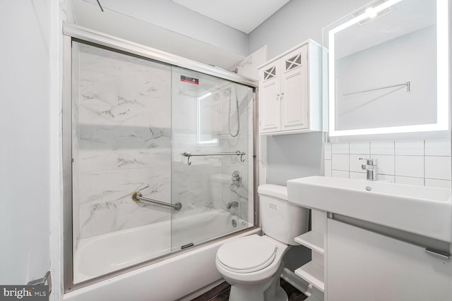 bathroom with combined bath / shower with glass door, backsplash, toilet, and vanity