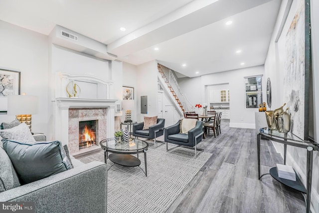 living room with recessed lighting, visible vents, a premium fireplace, wood finished floors, and stairs