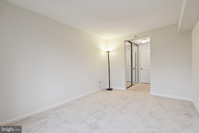 spare room with light colored carpet and baseboards