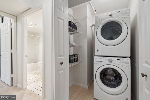 clothes washing area with stacked washer / drying machine and a textured ceiling