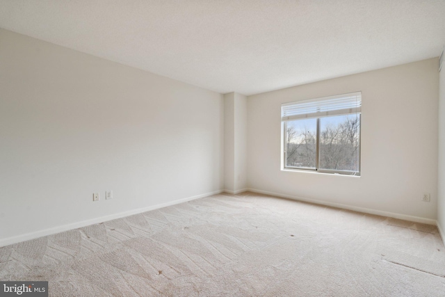 empty room featuring light colored carpet and baseboards