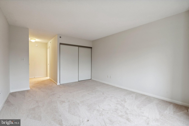 unfurnished bedroom with baseboards, a closet, and light colored carpet