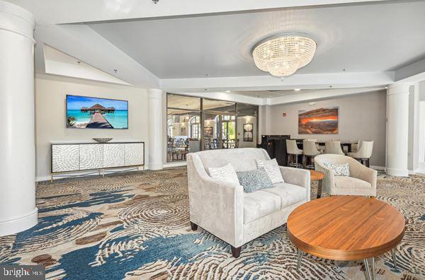 living room featuring decorative columns, a chandelier, and baseboards