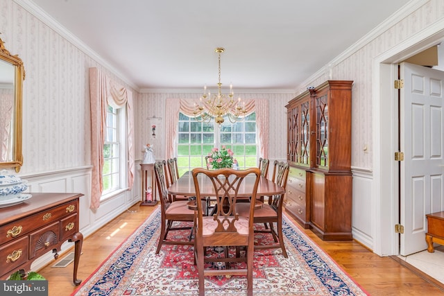 dining space featuring light hardwood / wood-style floors, crown molding, and a chandelier