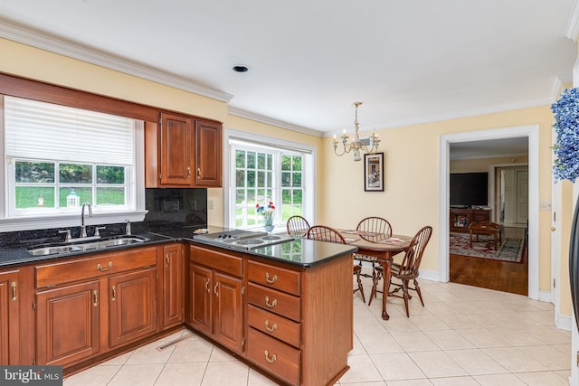 kitchen featuring plenty of natural light, crown molding, sink, and decorative light fixtures