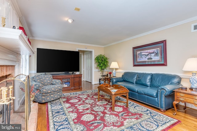 living room featuring hardwood / wood-style floors, a fireplace, and crown molding