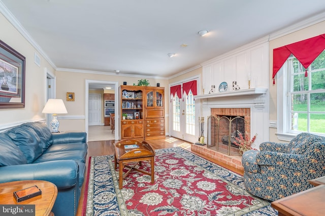 living room with wood-type flooring, a brick fireplace, and crown molding