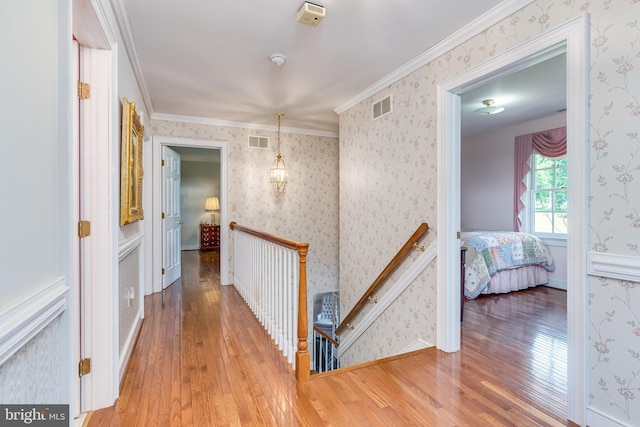 corridor with light hardwood / wood-style floors and ornamental molding