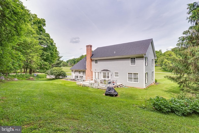 rear view of property featuring a yard and a wooden deck