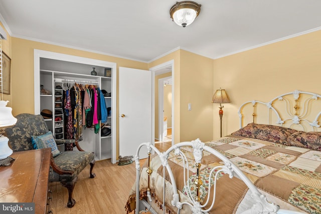 bedroom with wood-type flooring, crown molding, and a closet