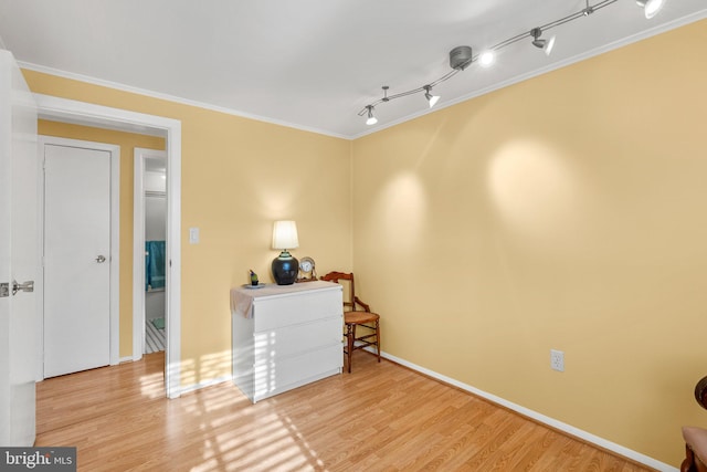 interior space with rail lighting, light hardwood / wood-style flooring, and crown molding