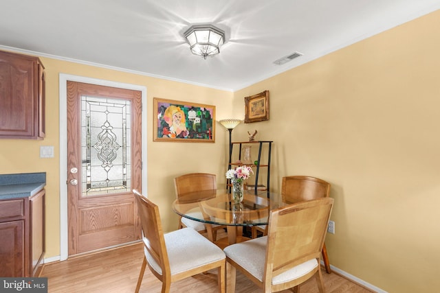 dining room with light hardwood / wood-style floors and crown molding