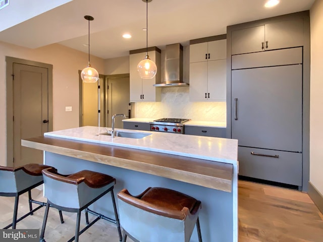 kitchen with a breakfast bar, tasteful backsplash, wall chimney exhaust hood, and sink