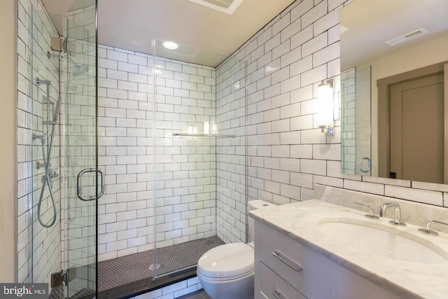 bathroom with vanity, a shower with door, backsplash, toilet, and tile walls