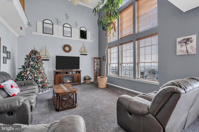 carpeted living room featuring ceiling fan, crown molding, and a towering ceiling