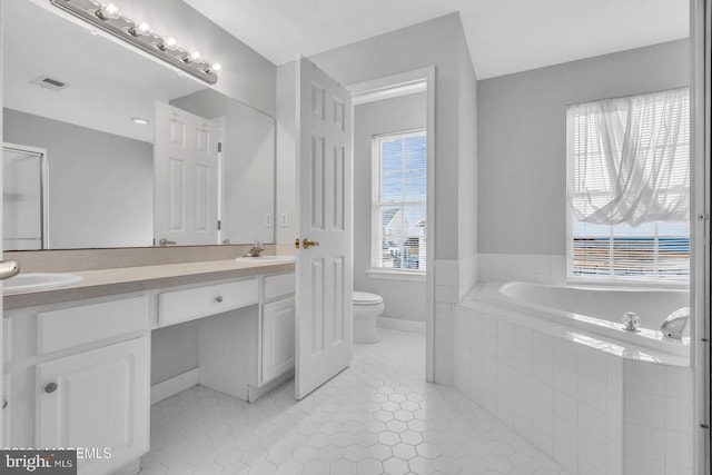 bathroom with tile patterned flooring, a relaxing tiled tub, and a healthy amount of sunlight