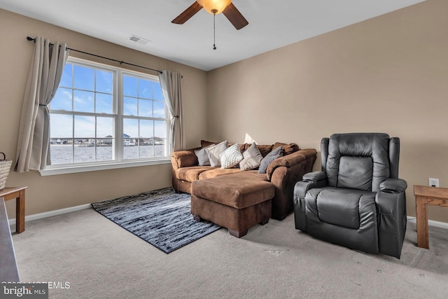 carpeted living room with ceiling fan and a water view