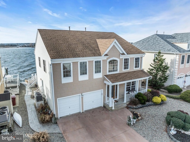 view of front of property with cooling unit, a water view, a porch, and a garage