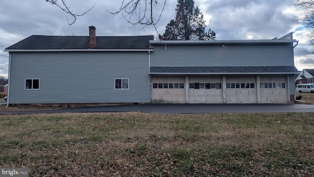 rear view of property featuring a garage and a lawn