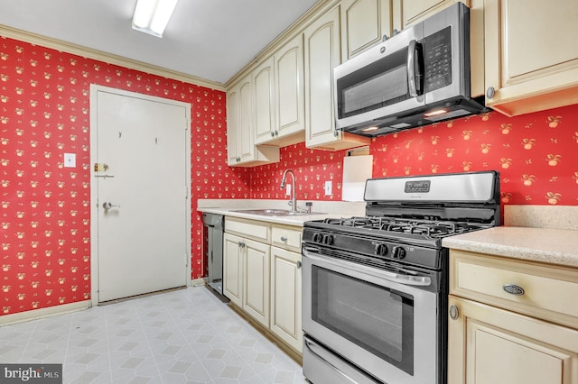 kitchen with cream cabinets, crown molding, sink, and stainless steel appliances