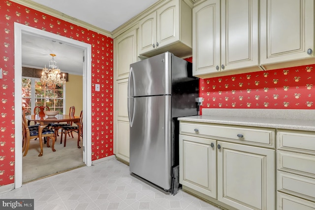 kitchen featuring light colored carpet, crown molding, cream cabinetry, a chandelier, and stainless steel refrigerator