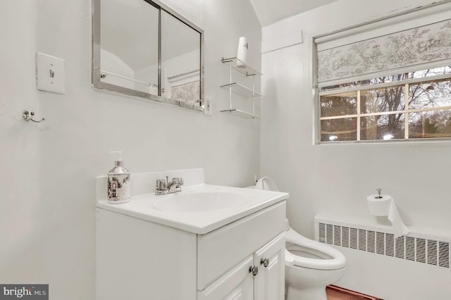 bathroom with radiator heating unit, vanity, and toilet