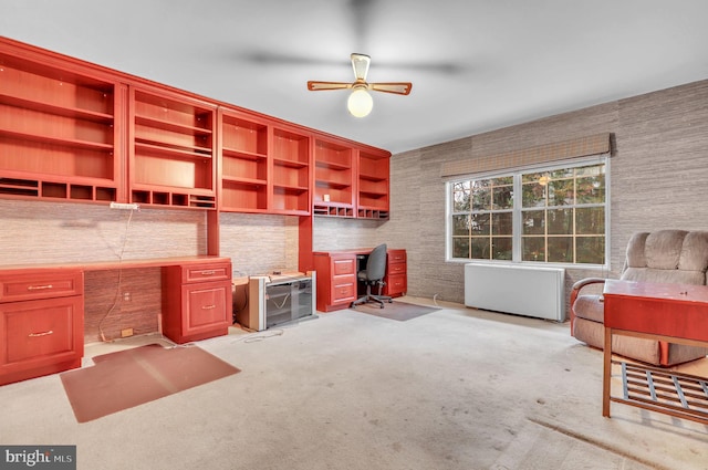 carpeted office featuring ceiling fan and built in desk