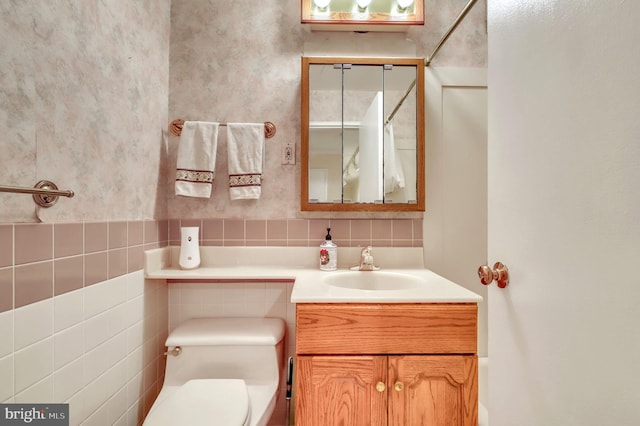 bathroom featuring walk in shower, vanity, tile walls, and toilet