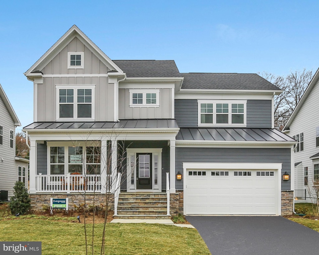 craftsman house featuring covered porch, a garage, and a front lawn