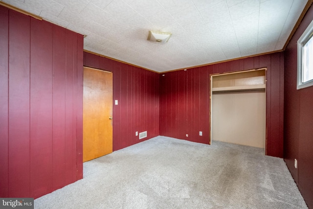 unfurnished bedroom featuring wood walls, a closet, and carpet