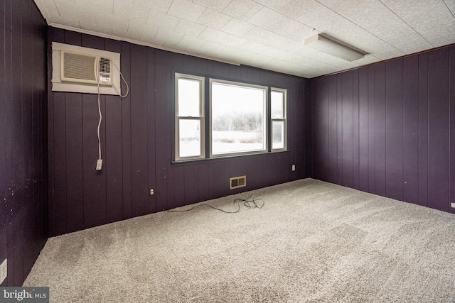 carpeted empty room featuring an AC wall unit and wooden walls