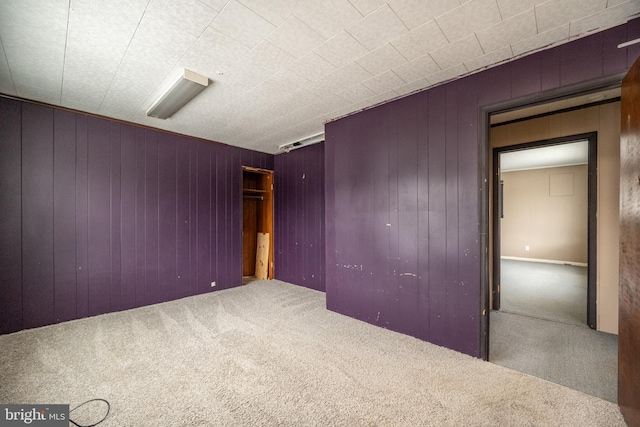 carpeted empty room with wood walls