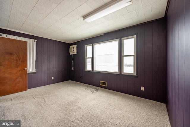 carpeted spare room featuring a wall unit AC and wood walls