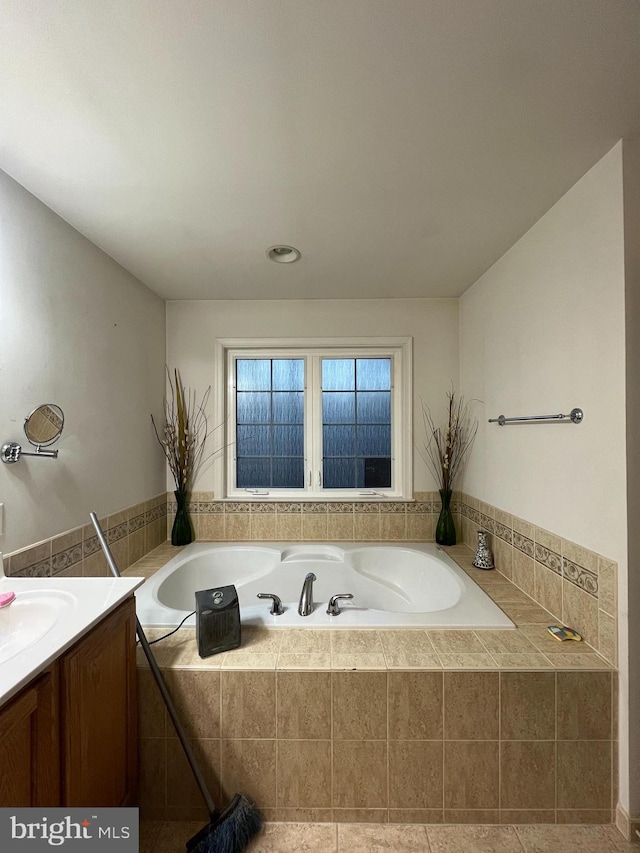 bathroom featuring tile patterned flooring, vanity, and a relaxing tiled tub