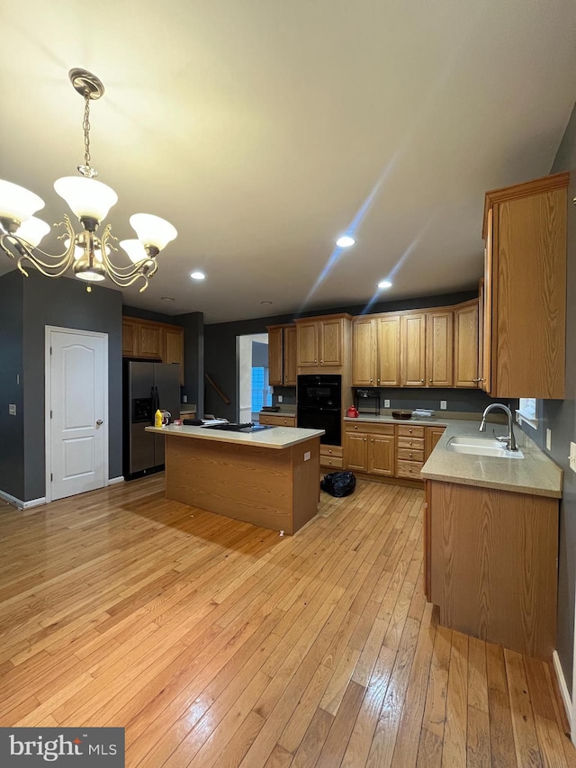 kitchen featuring sink, light hardwood / wood-style flooring, stainless steel refrigerator with ice dispenser, a notable chandelier, and a kitchen island