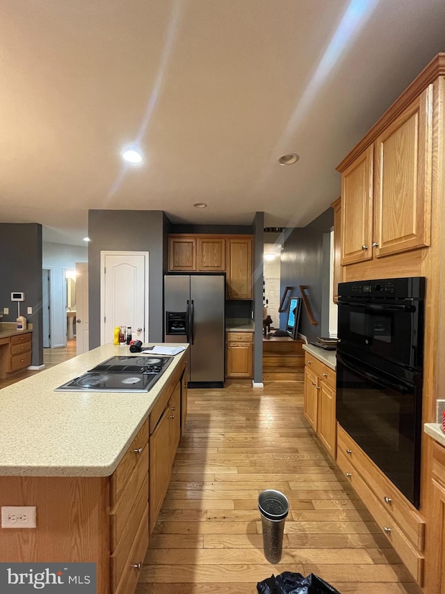 kitchen with light hardwood / wood-style flooring, a kitchen island, and black appliances